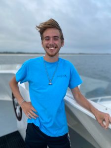 a man in a blue shirt standing in front of a body of water
