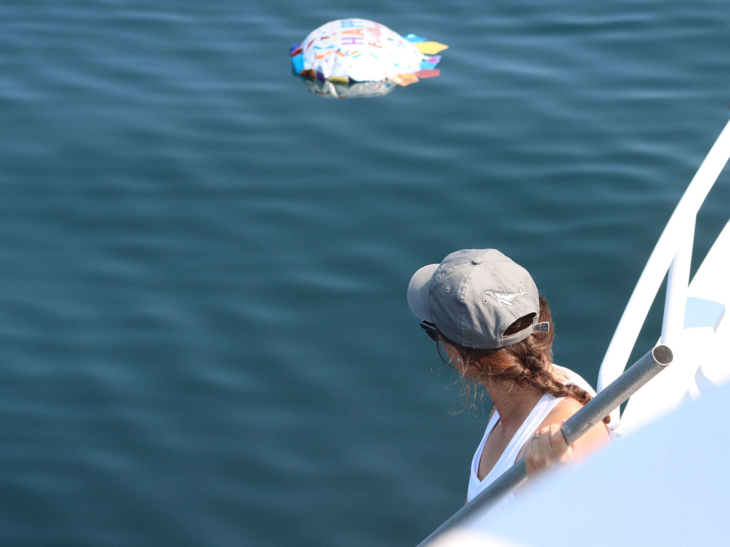 Person on a boat looking at a floating balloon in the water.