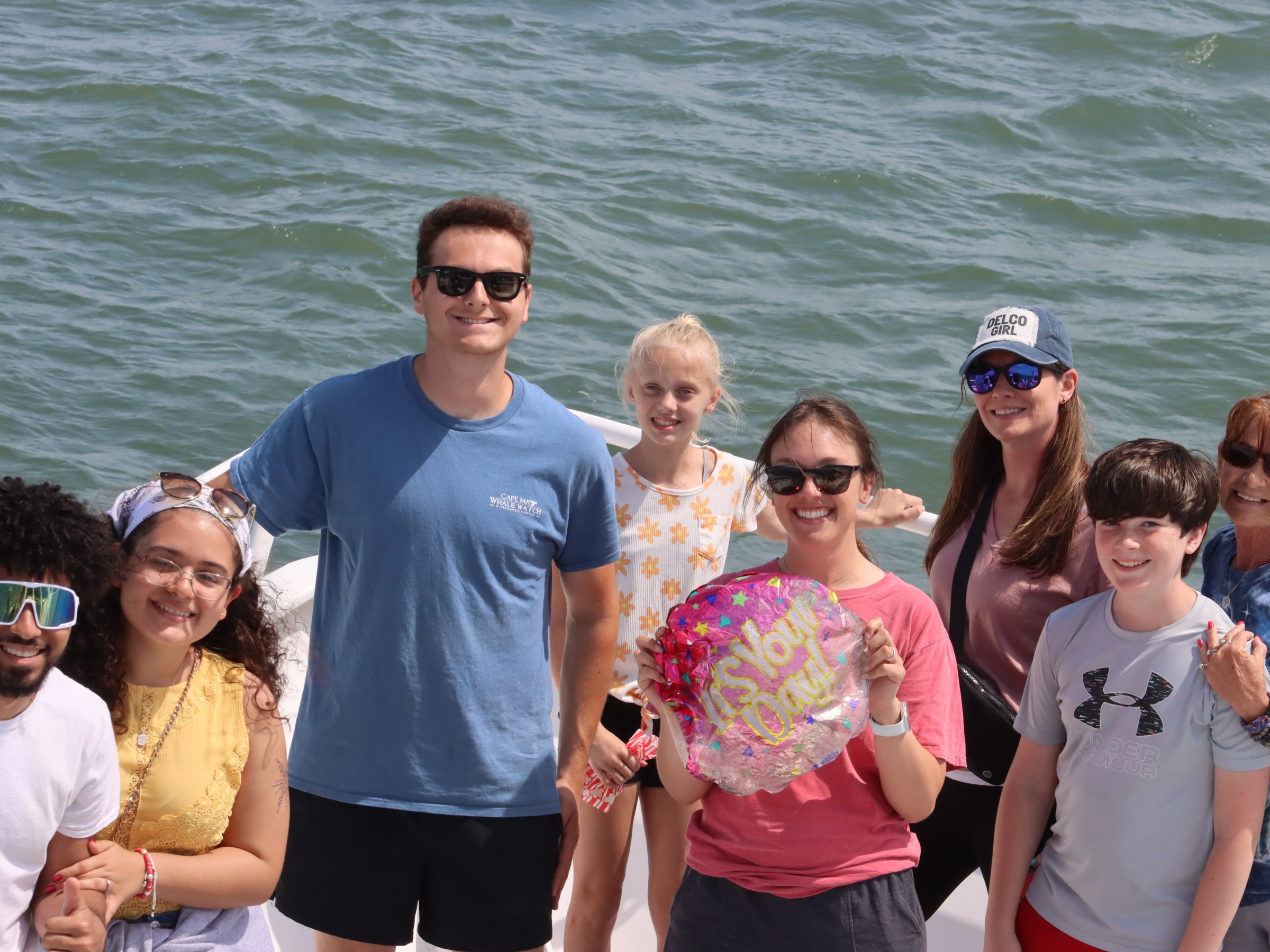 Group of people smiling on a boat with water in the background.
