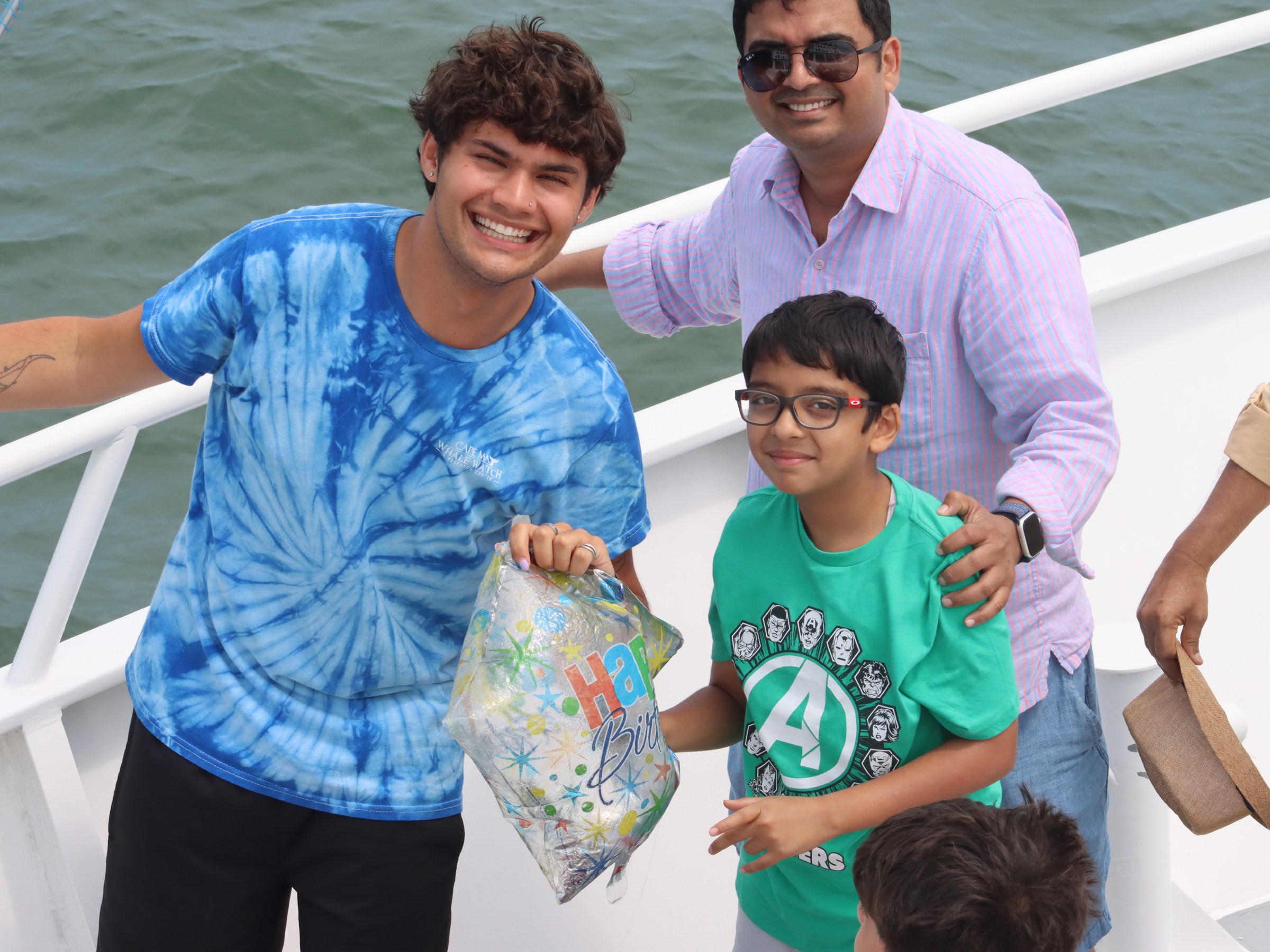 Group of people smiling on a boat with a birthday balloon.