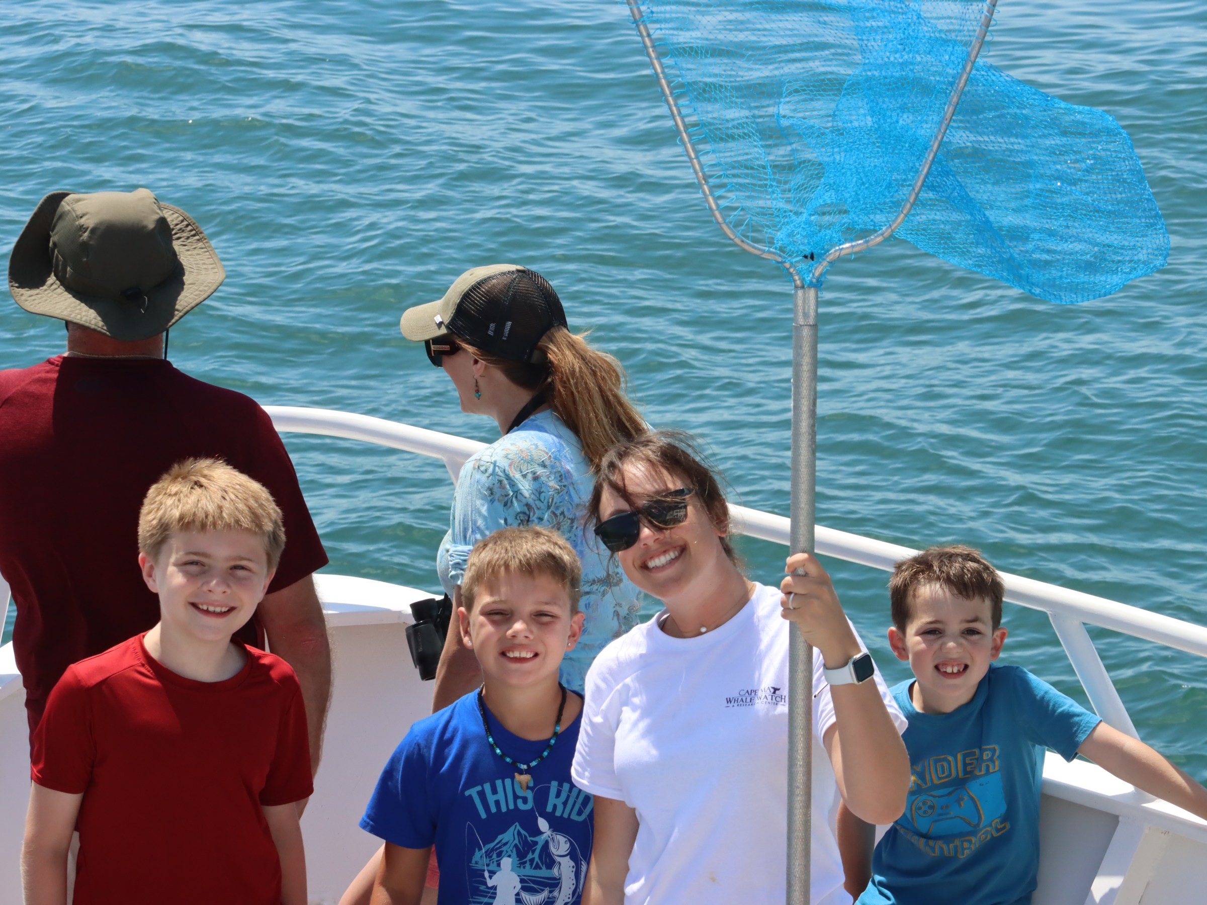 Five people on a boat, with one holding a blue fishing net.